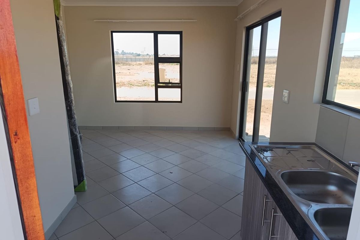 An open-plan living and kitchen area featuring tiled flooring, modern cabinetry with granite countertops, and large windows providing natural light.