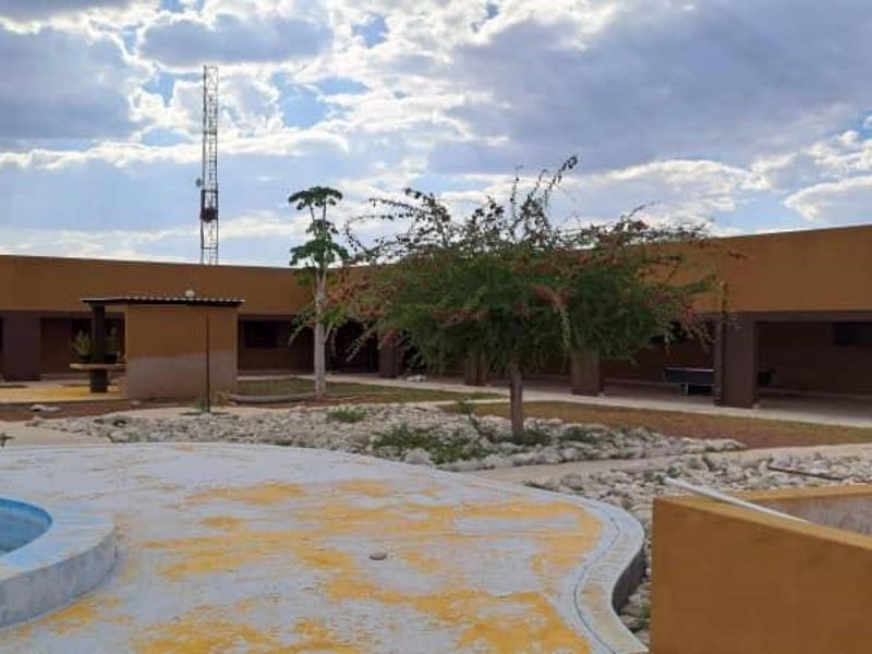 Rear exterior view of the farm property featuring a swimming pool, covered patio areas, and a communication tower set against a large courtyard.