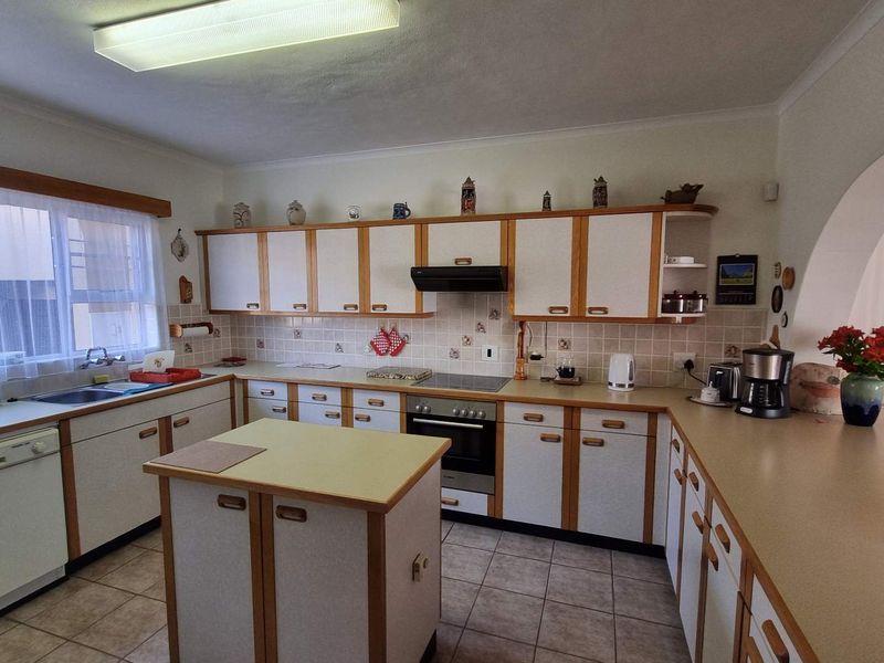 A functional kitchen featuring classic white and wood-trim cabinetry, a central island, tiled backsplash, and integrated cooking appliances.