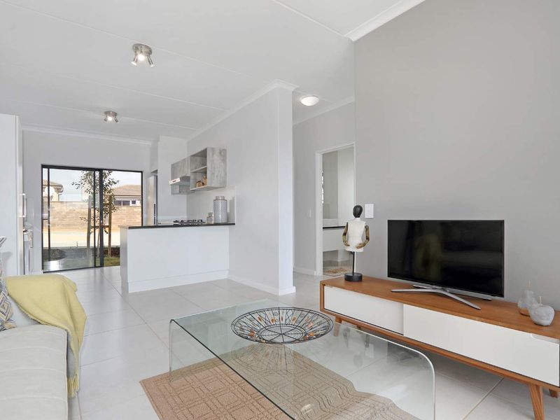 Modern open-plan living area featuring tiled floors, a functional kitchen with built-in cabinetry, and direct access to an outdoor space via sliding glass doors.