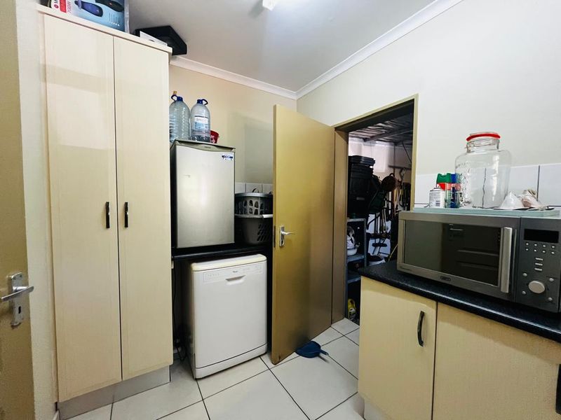 A functional laundry area featuring built-in cabinetry, laminate countertops, and tiled flooring, providing practical storage and utility space.