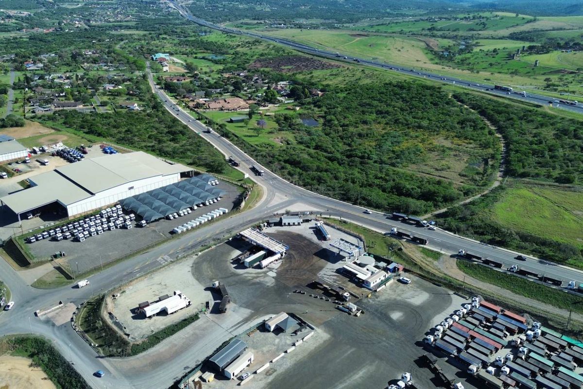 Aerial view of an industrial property featuring a large warehouse, extensive paved yard, fueling infrastructure, and direct access to major transport routes.