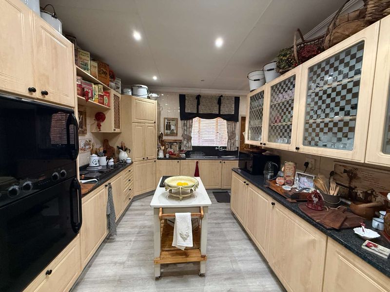 A well-appointed kitchen featuring light wood cabinetry, granite countertops, a double wall oven, and a central island, offering ample storage and workspace.