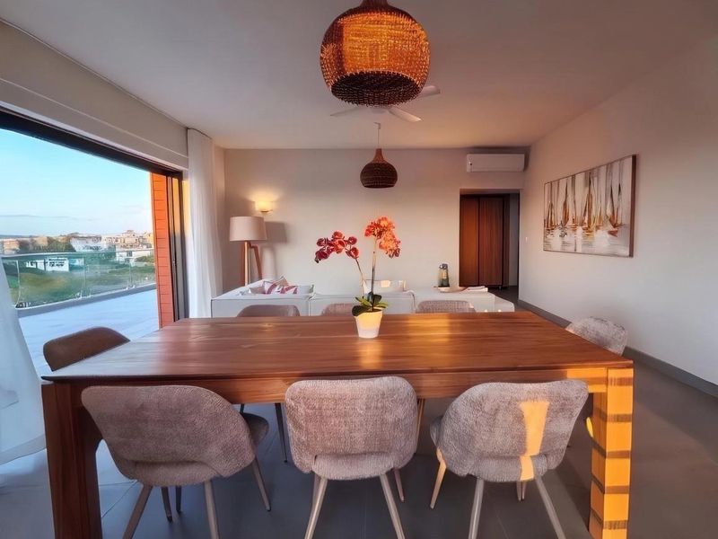 Spacious open-plan living and dining area featuring tiled floors, split-system air conditioning, and large sliding glass doors opening to a balcony with scenic views.