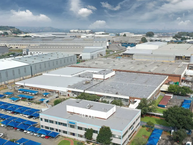 Aerial view of a large industrial complex featuring multiple warehouse structures, office buildings, and extensive covered parking facilities within a commercial estate.