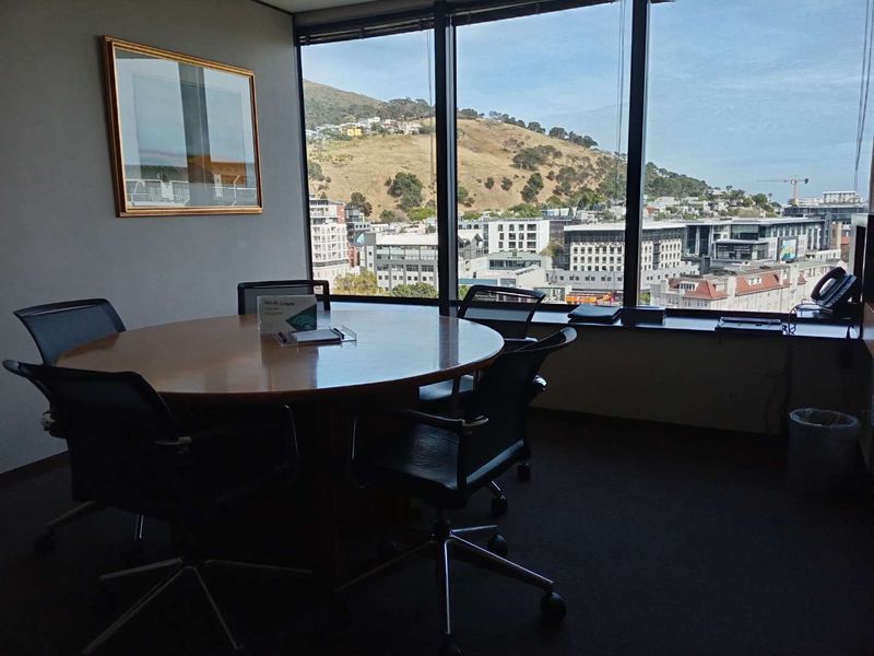 A professional office space featuring large floor-to-ceiling windows with expansive city and mountain views.