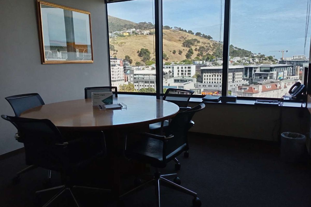 A professional office space featuring large floor-to-ceiling windows with expansive city and mountain views.