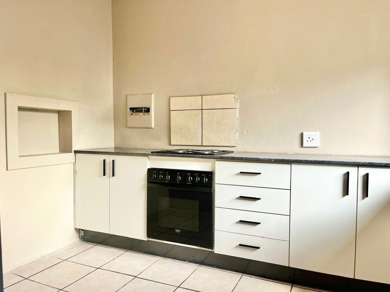 A functional kitchen area featuring built-in cabinetry, an integrated oven and hob, tiled flooring, and a wall-mounted distribution board.