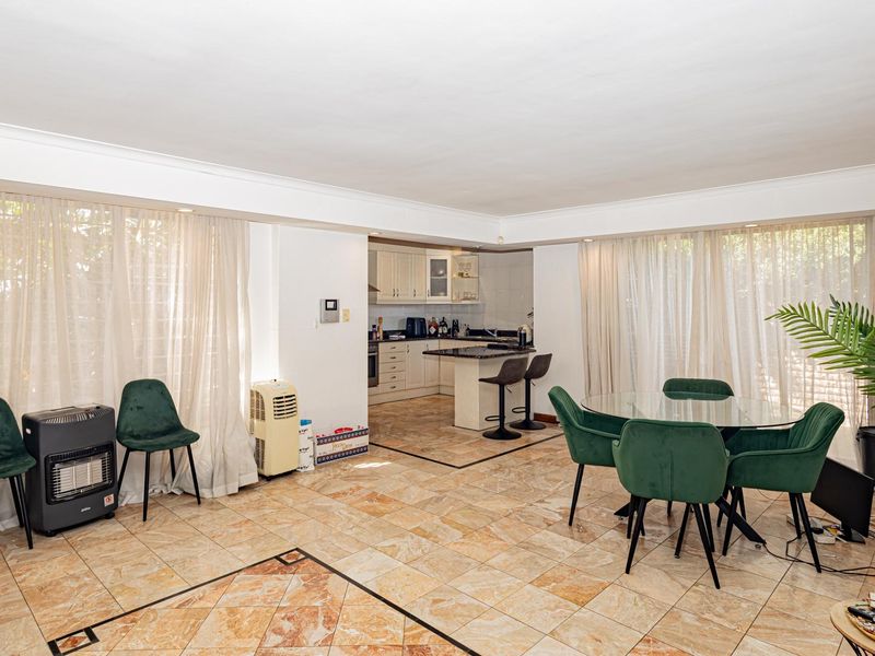 Spacious open-plan living and dining area featuring tiled flooring, recessed lighting, and a functional kitchen with built-in cabinetry and a central island.