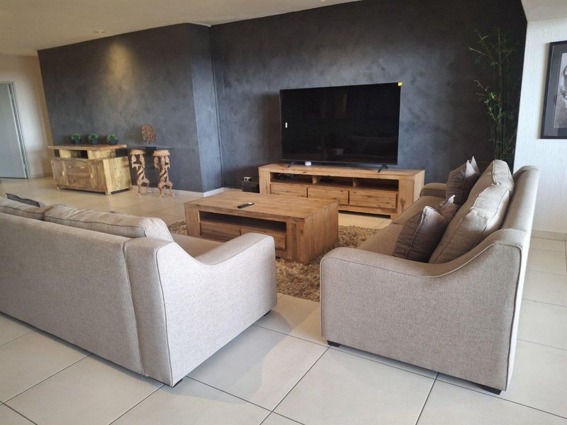 A spacious living room featuring large format floor tiles and a dark textured feature wall, creating a modern and comfortable atmosphere.