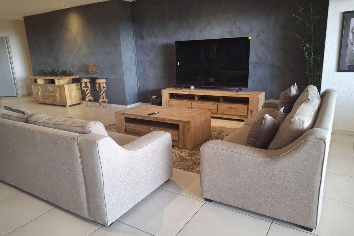 A spacious living room featuring large format floor tiles and a dark textured feature wall, creating a modern and comfortable atmosphere.