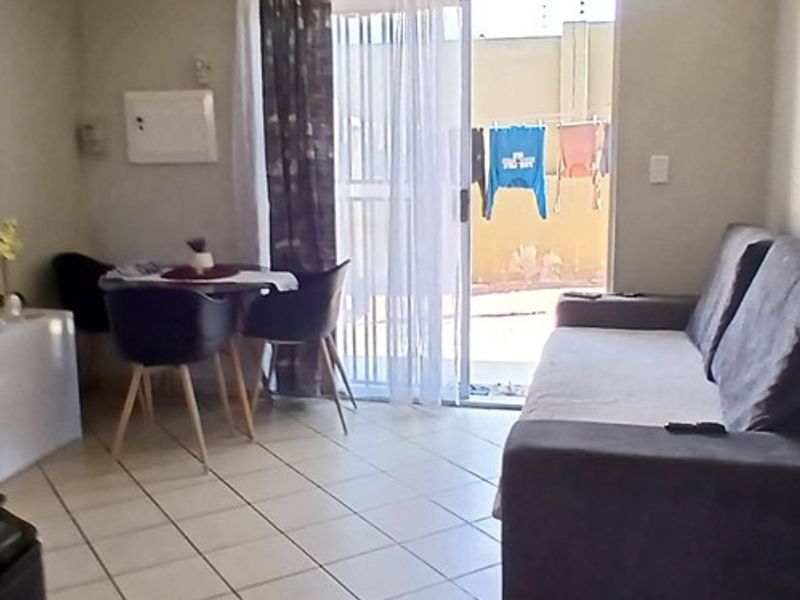 A living room featuring tiled flooring and a sliding glass door providing access to an outdoor area.