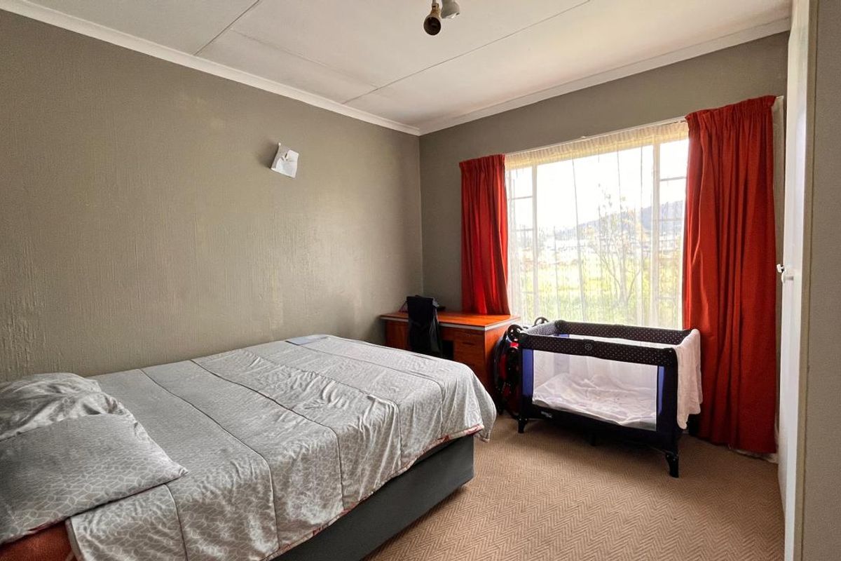 A bedroom featuring carpeted flooring, a large window with curtains, and neutral wall finishes.