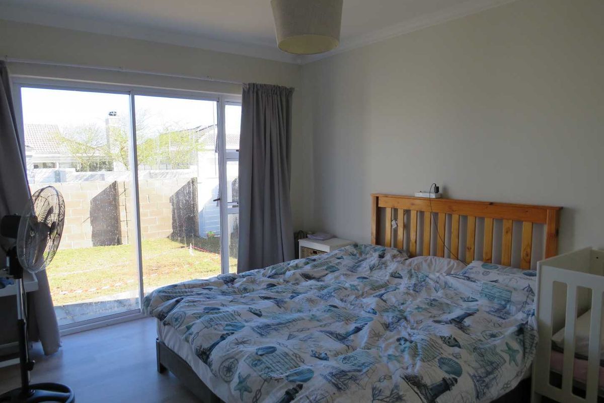 A bedroom featuring laminate flooring and a large sliding glass door providing direct access to the rear garden area.