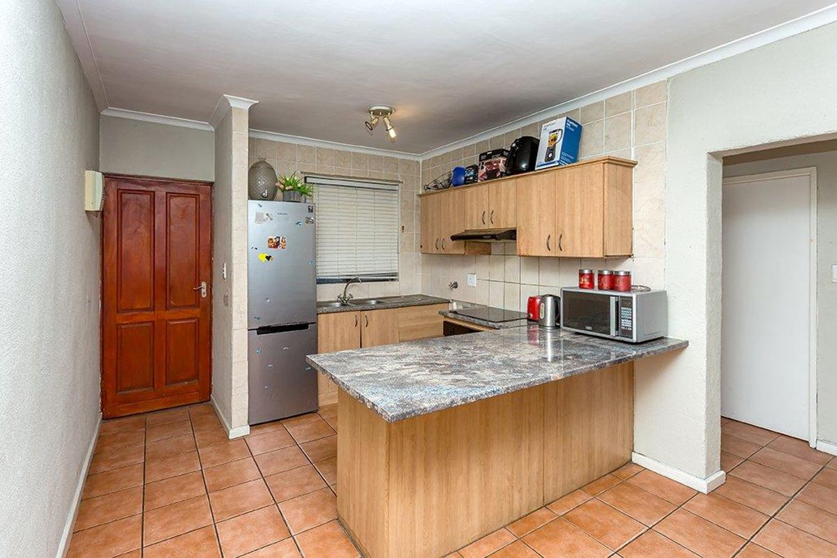 Functional kitchen featuring laminate cabinetry, a breakfast bar, ceramic tile flooring, and a tiled backsplash, offering a practical layout for daily use.
