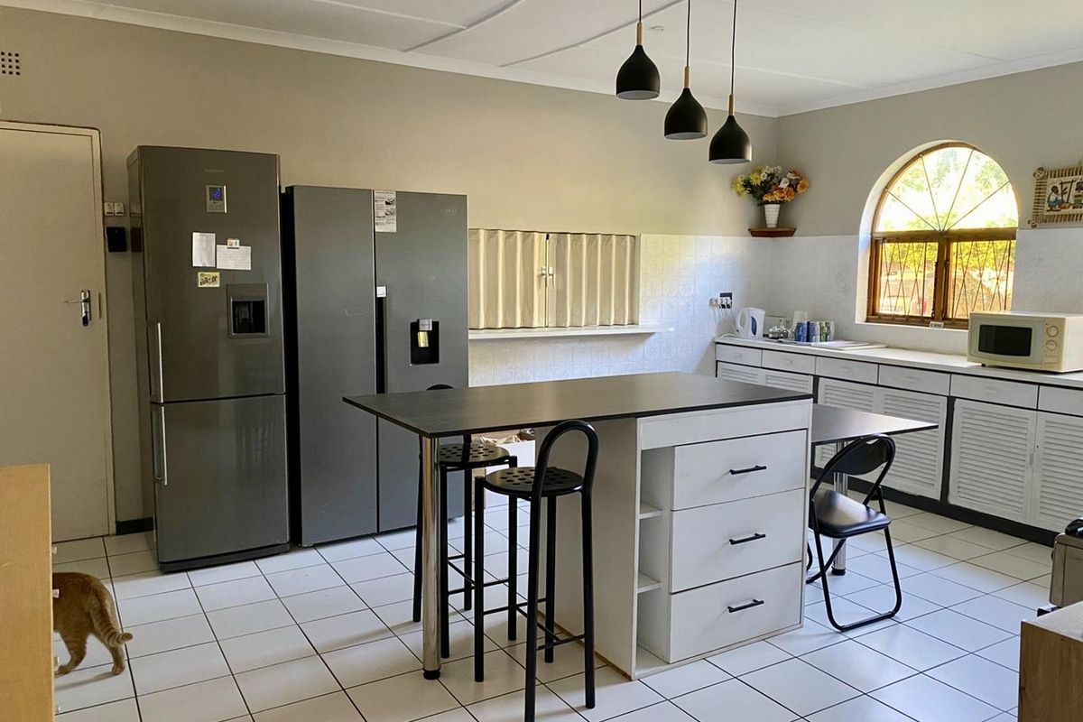Kitchen featuring a central island with storage, tiled flooring, and an arched window, providing a functional workspace with ample cabinetry.