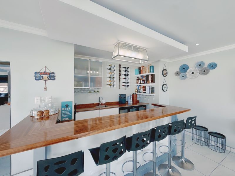 A well-appointed home bar area featuring a polished wooden countertop, built-in cabinetry, integrated wine storage, and a functional sink.