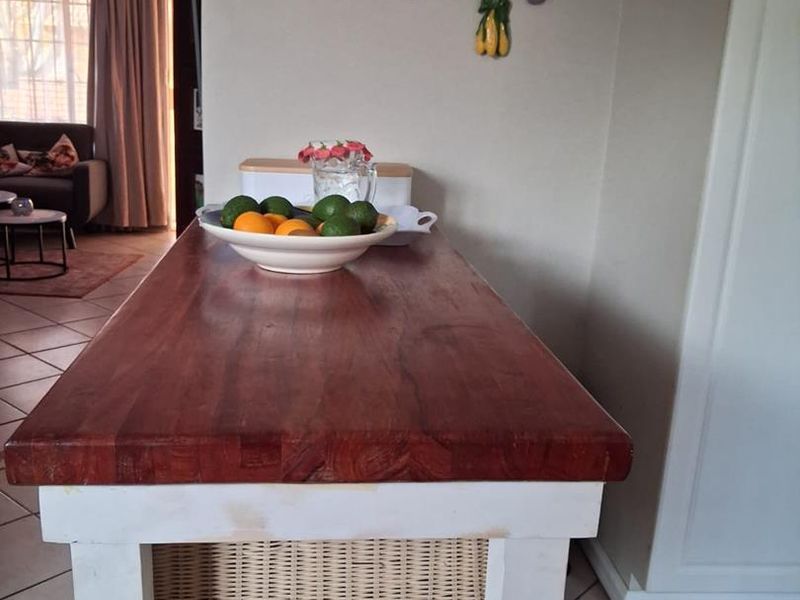 A kitchen area featuring a wooden island with a tiled floor, showing a view into the adjacent living space.