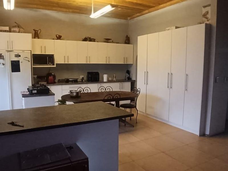 Spacious kitchen featuring extensive built-in cabinetry, timber ceiling, and tiled flooring, currently requiring finishing touches to walls and ceiling to reach full potential.