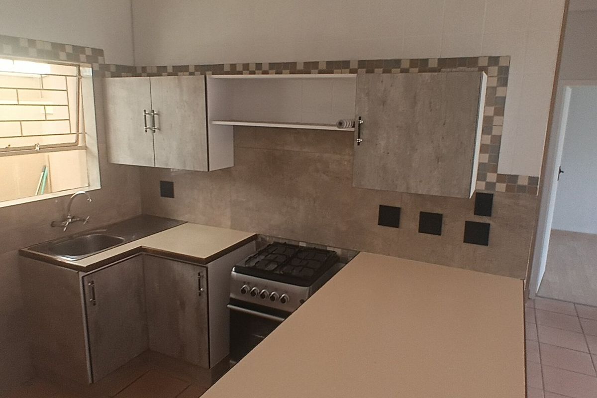 A functional kitchen featuring built-in cabinetry, a gas stove, and tiled backsplash, offering a clean and practical workspace.