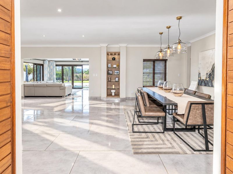 Spacious open-plan living and dining area featuring polished tile flooring, recessed lighting, and large sliding glass doors leading to the outdoor space.