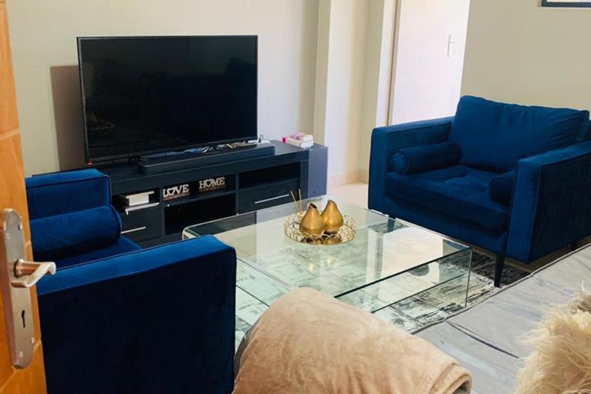 A comfortable living room featuring neutral wall tones, tiled flooring, and a recessed wall section suitable for media placement.