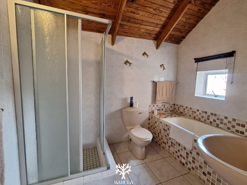 A bathroom featuring a shower enclosure, built-in bathtub, toilet, and exposed timber ceiling beams with mosaic tile accents.