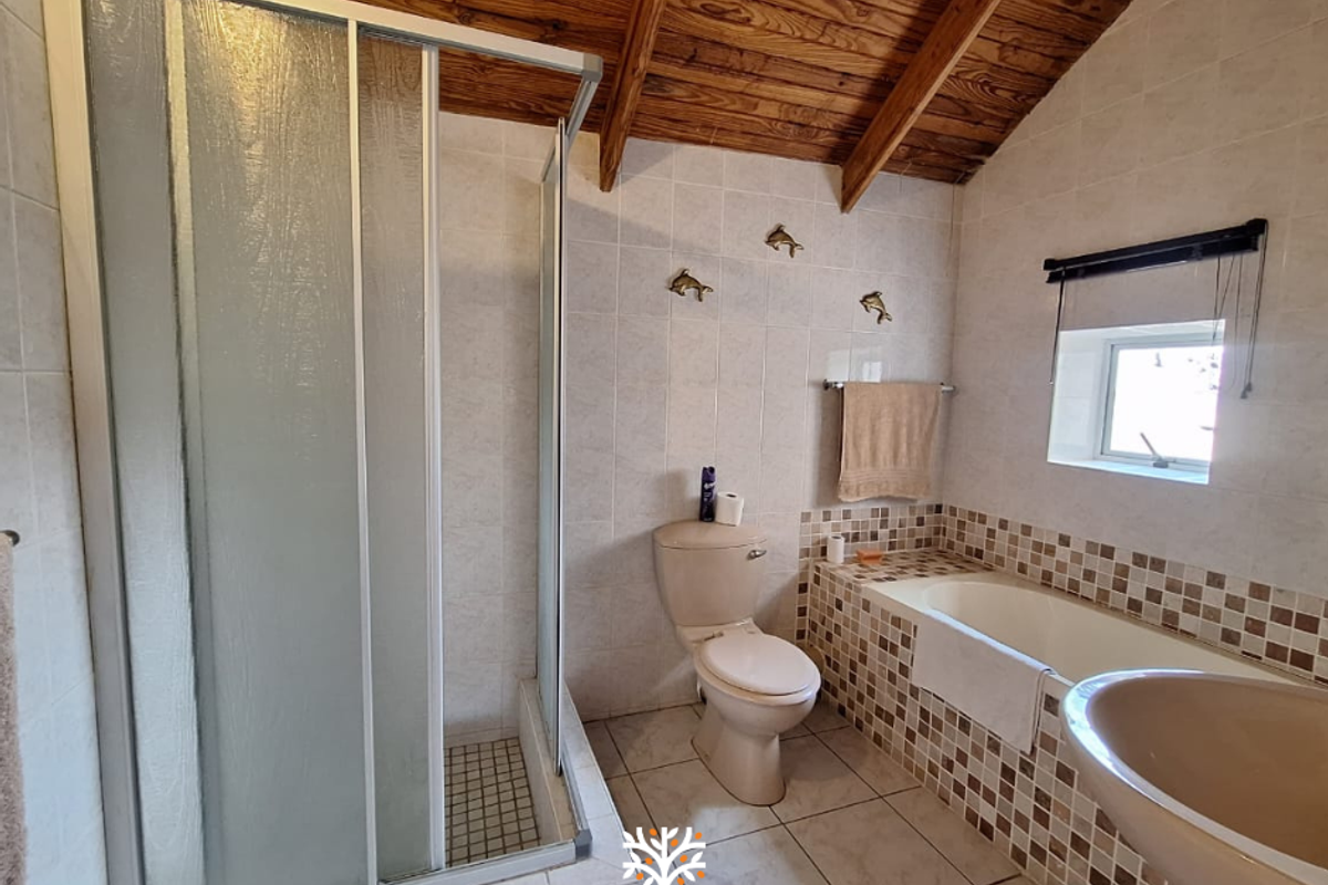 A bathroom featuring a shower enclosure, built-in bathtub, toilet, and exposed timber ceiling beams with mosaic tile accents.