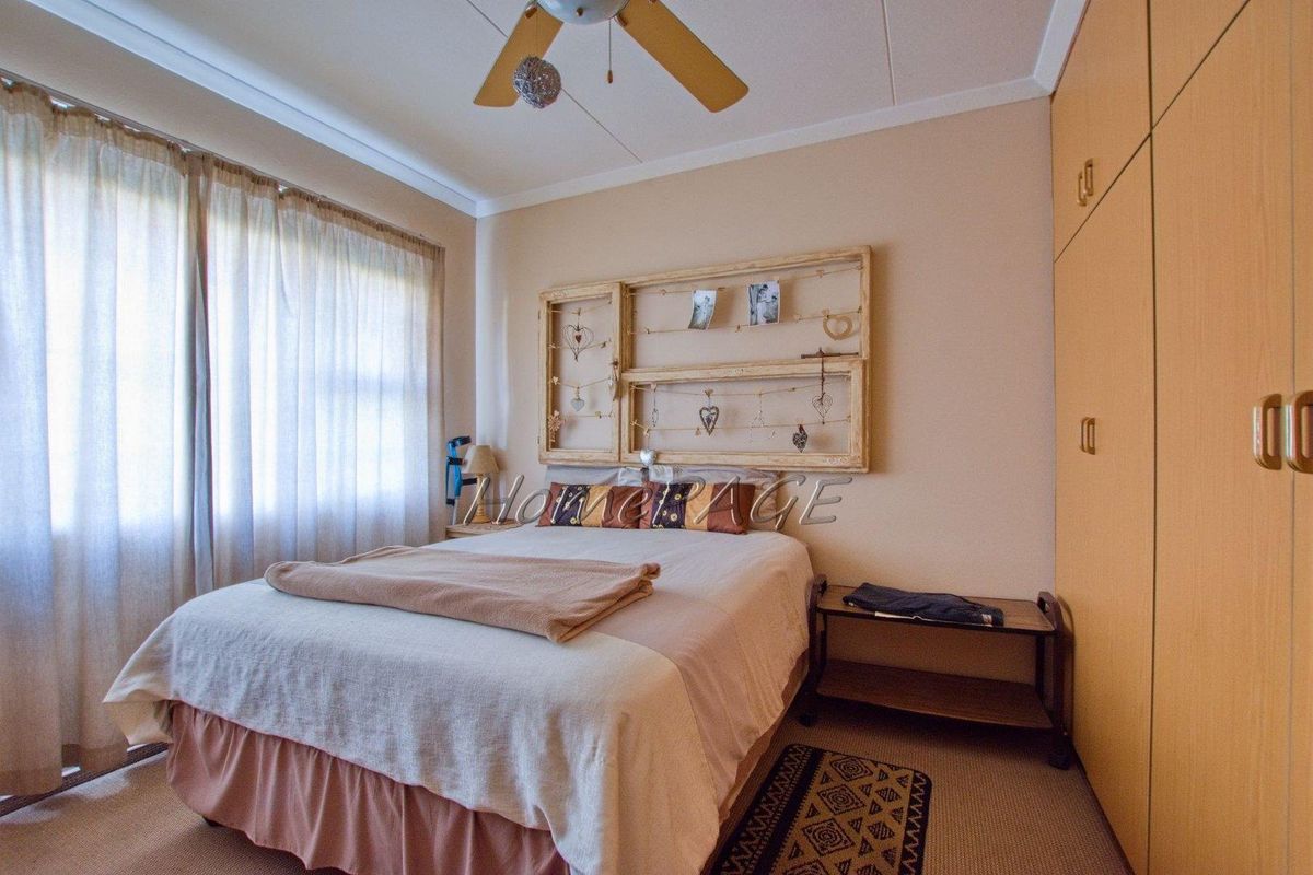A bedroom featuring built-in wooden cabinetry and a ceiling fan, providing functional storage and climate control.