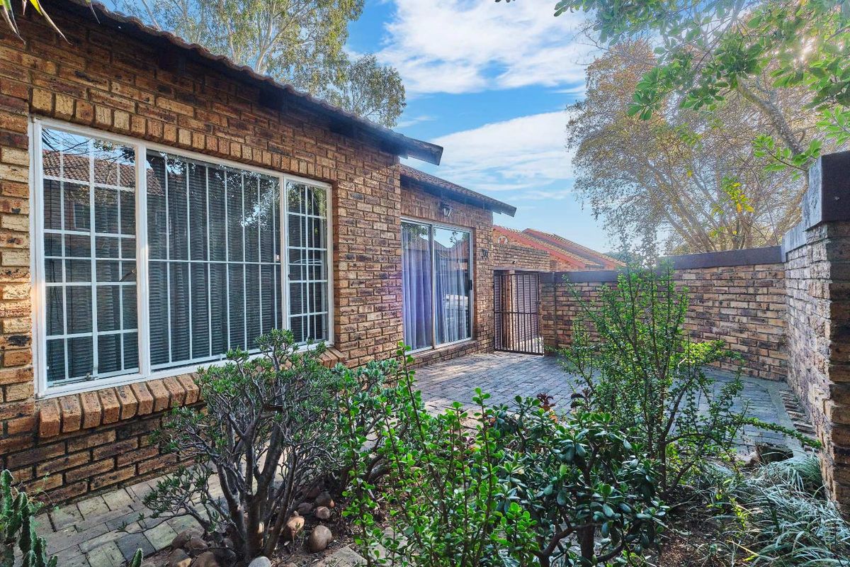 A private rear courtyard featuring a paved patio area, face brick exterior walls, and secure sliding door access to the townhouse interior.