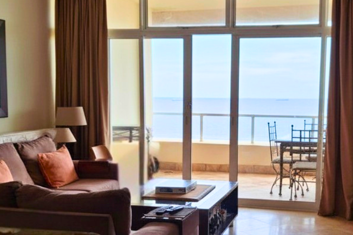 Living room featuring large sliding glass doors that open onto a balcony with ocean views, providing ample natural light.