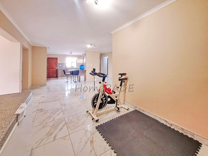 Spacious open-plan living and kitchen area featuring modern marble-look floor tiles and neutral wall finishes.