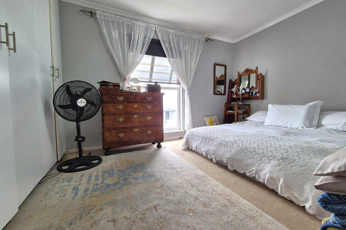 A well-proportioned bedroom featuring neutral wall tones, carpeted flooring, and a built-in wardrobe, offering a comfortable and functional living space.