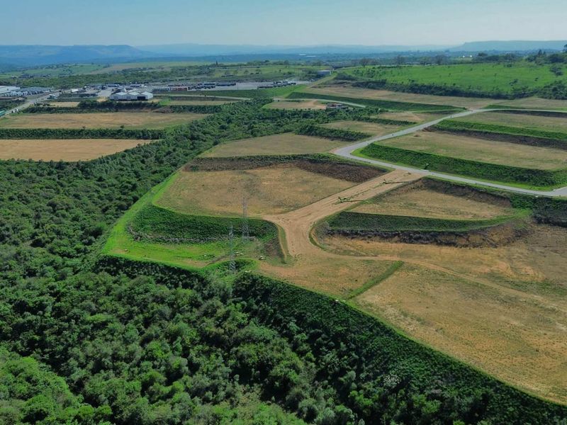 Aerial view of a large industrial development site featuring terraced land, established access roads, and surrounding natural vegetation.