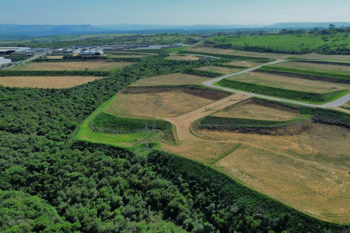 Aerial view of a large industrial development site featuring terraced land, established access roads, and surrounding natural vegetation.