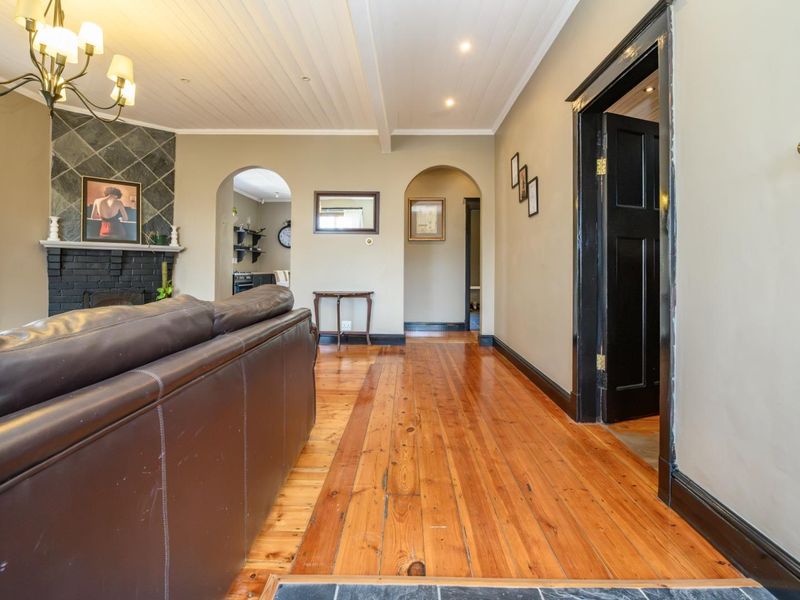 Spacious living room featuring polished timber flooring, a stone-surround fireplace, and classic architectural archways leading to adjacent living areas.