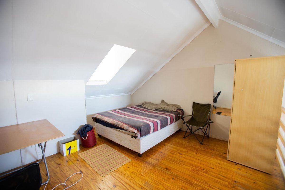A loft-style bedroom featuring vaulted ceilings, exposed timber flooring, and a skylight window providing natural light.
