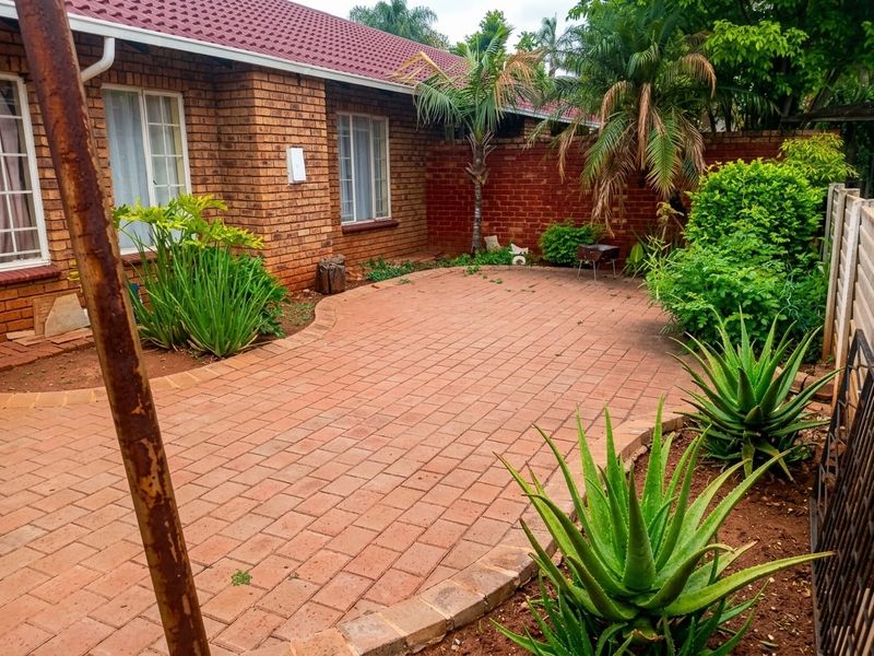 A private rear courtyard featuring brick paving, established garden beds, and a brick boundary wall, providing a low-maintenance outdoor living space.