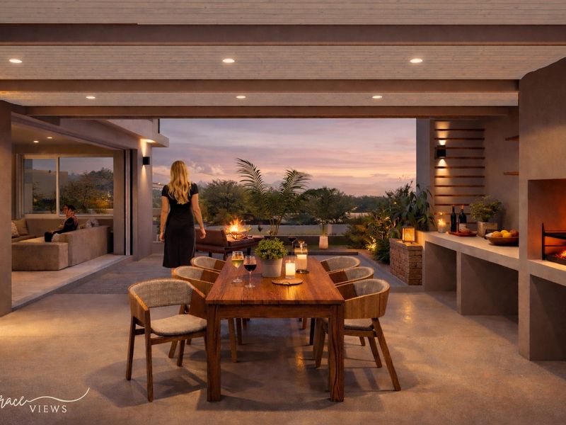 A spacious covered patio featuring a built-in fireplace, recessed lighting, and a seamless transition to an outdoor living area with sunset views.