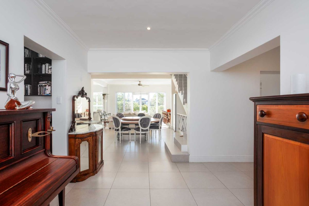 Spacious open-plan living and dining area featuring neutral tiled flooring, recessed lighting, and a staircase, creating a bright and airy atmosphere.