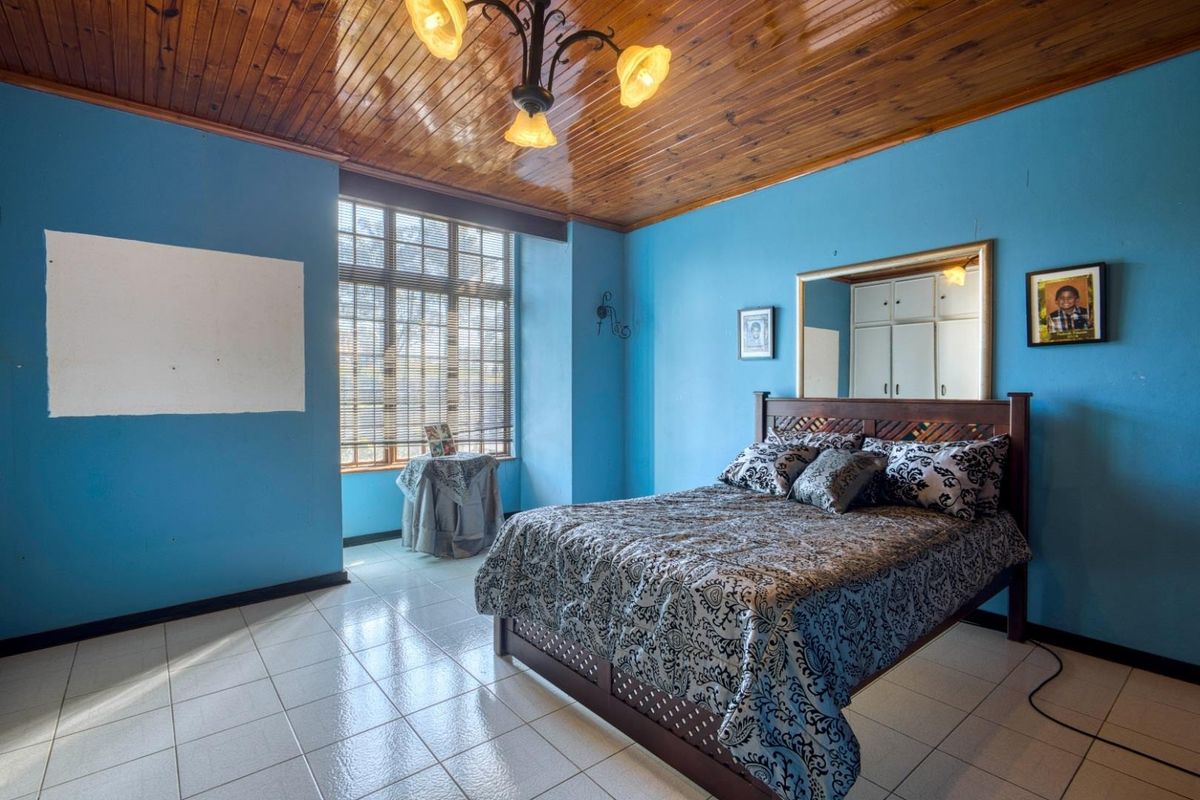 Spacious bedroom featuring a timber tongue and groove ceiling, ceramic tiled flooring, and built-in storage cupboards.