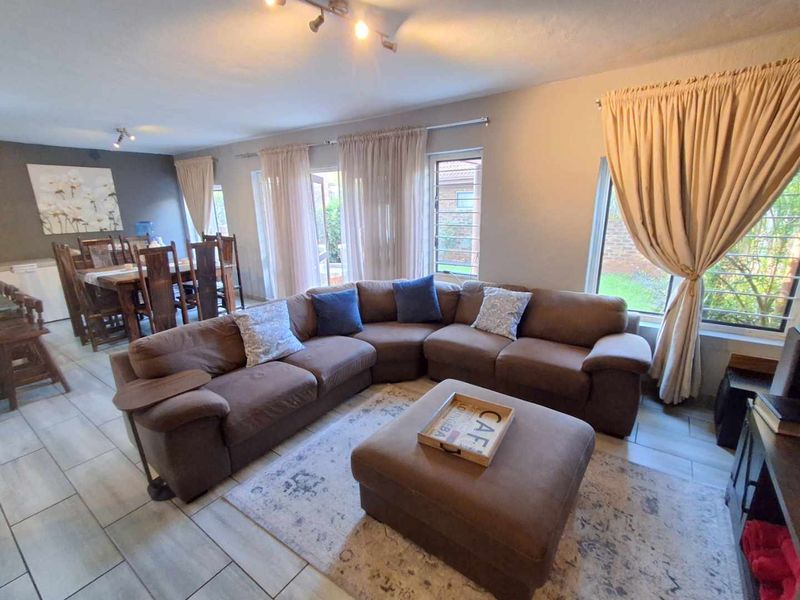 Spacious open-plan living and dining area featuring tiled flooring, large sliding glass doors, and ample natural light through louvered windows.