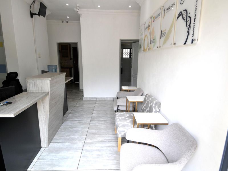 A professional reception area featuring a modern reception desk, tiled flooring, and recessed lighting, suitable for a business or medical office environment.