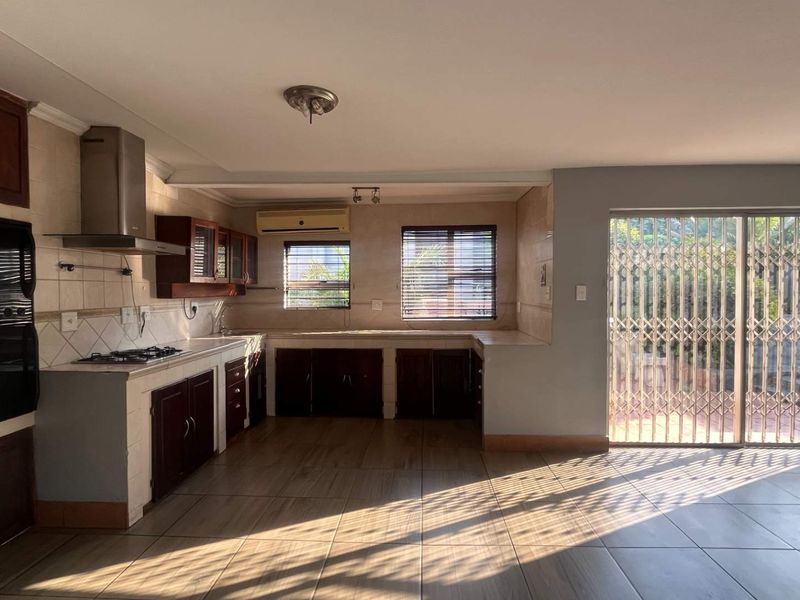 Spacious open-plan kitchen featuring built-in cabinetry, gas hob, and oven, with direct access to an outdoor area through sliding glass doors.