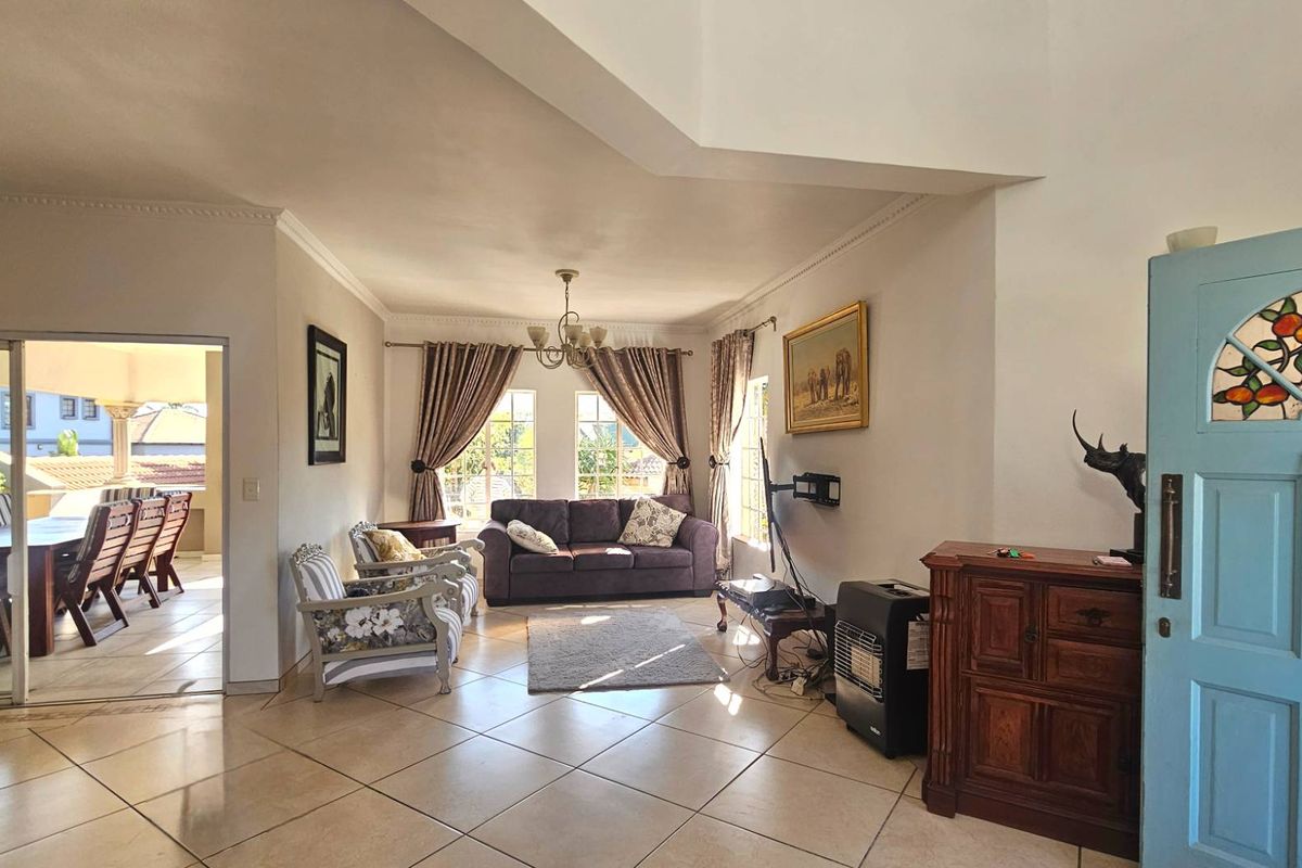 Spacious living area featuring tiled flooring, decorative ceiling cornices, and a distinctive blue front door with stained glass detailing.