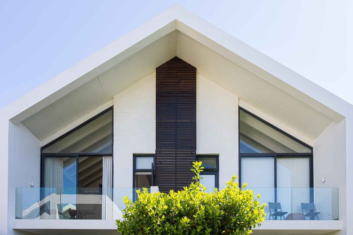 Modern architectural rear facade featuring a pitched roof, timber accent cladding, and glass balustrades on the upper level balconies.