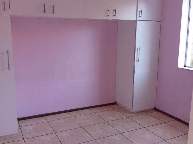 A vacant bedroom featuring built-in white cupboards and tiled flooring, offering a blank canvas for potential updates and personalization.