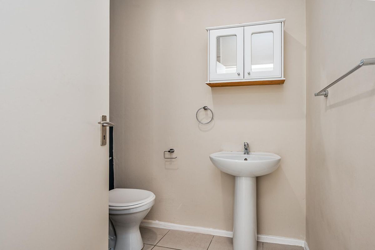A compact guest bathroom featuring a pedestal sink, a wall-mounted mirrored medicine cabinet, and a standard toilet.