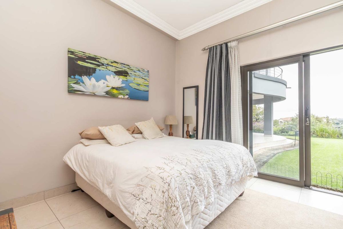 A bright bedroom featuring tiled flooring, crown molding, and large sliding glass doors providing direct access to the garden and patio area.