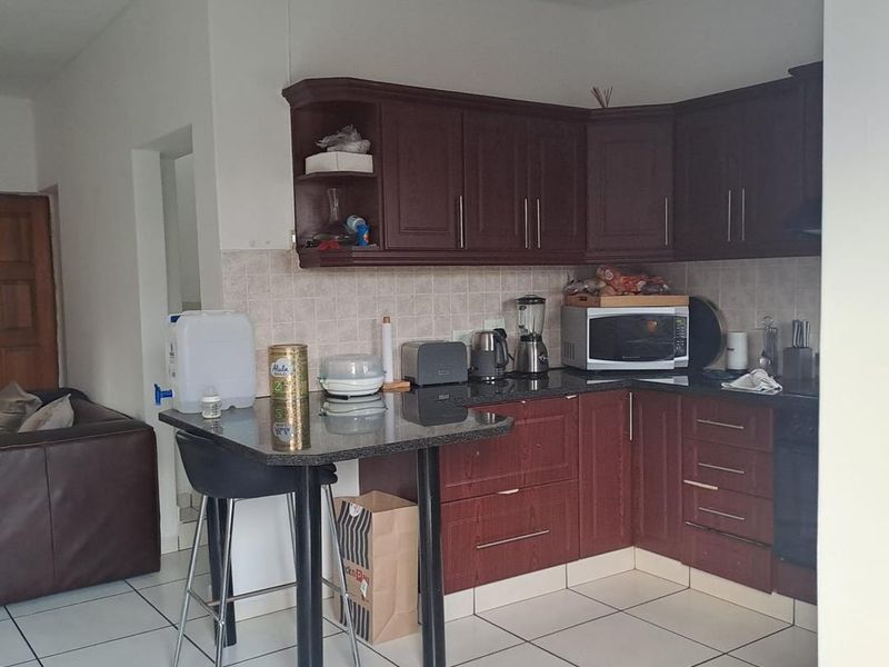 A functional kitchen featuring dark wood cabinetry, granite countertops, a breakfast bar, and tiled flooring, offering a practical layout for daily use.